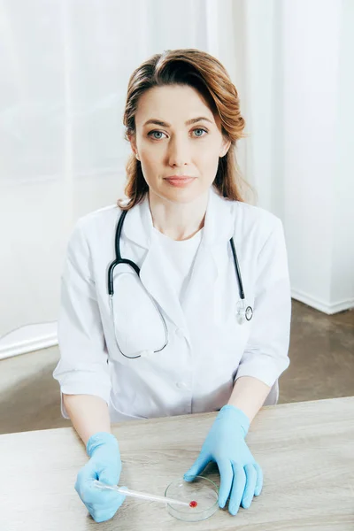 Arzt in weißem Mantel und Latexhandschuhen mit Pipette und Blutprobe — Stockfoto