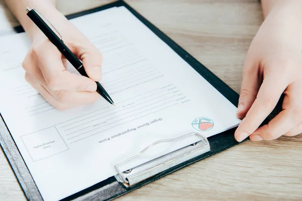 Vue recadrée du formulaire d'enregistrement de la signature du donneur sur une surface en bois — Photo de stock