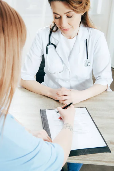 Vue recadrée du formulaire d'enregistrement de la signature du donneur et du médecin en manteau blanc — Photo de stock