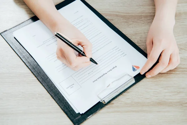 Vista parcial del formulario de registro de firma de donante en superficie de madera - foto de stock