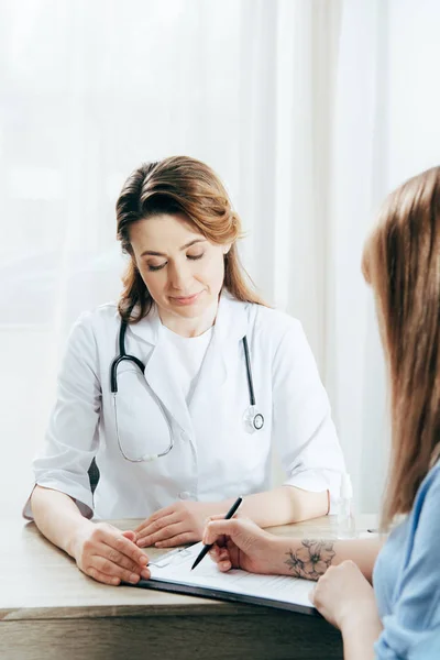 Vue recadrée du formulaire d'enregistrement de la signature du donneur et du médecin en manteau blanc — Photo de stock