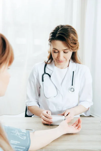 Vista recortada del paciente y el médico que mide la presión arterial - foto de stock