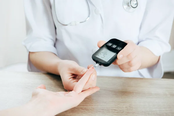 Vista recortada del donante y el médico que mide el nivel de glucosa con el glucosímetro — Stock Photo