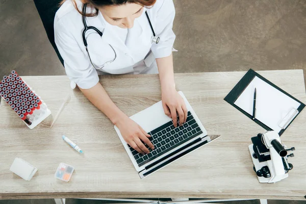 Overhead view of doctor in white coat using laptop — Stock Photo