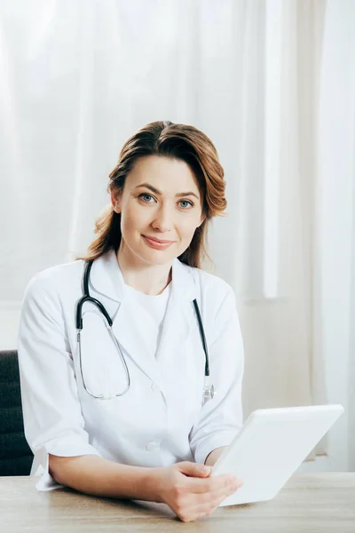 Smiling doctor in white coat with stethoscope using digital tablet in clinic — Stock Photo