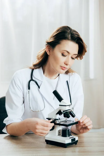Doctor in white coat using microscope in clinic — Stock Photo
