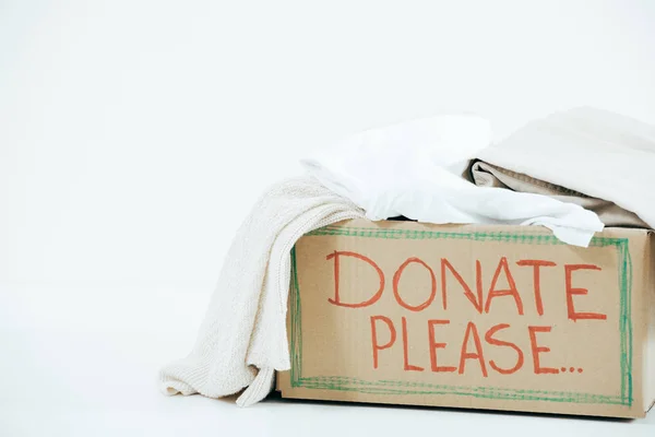Cardboard box with inscription and donated clothes on white — Stock Photo