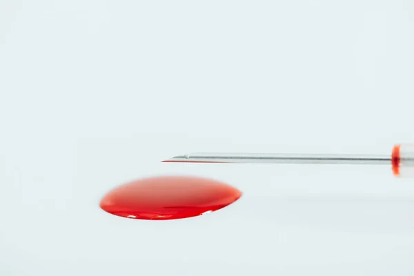 Aguja de jeringa y mancha de sangre aislada en blanco - foto de stock