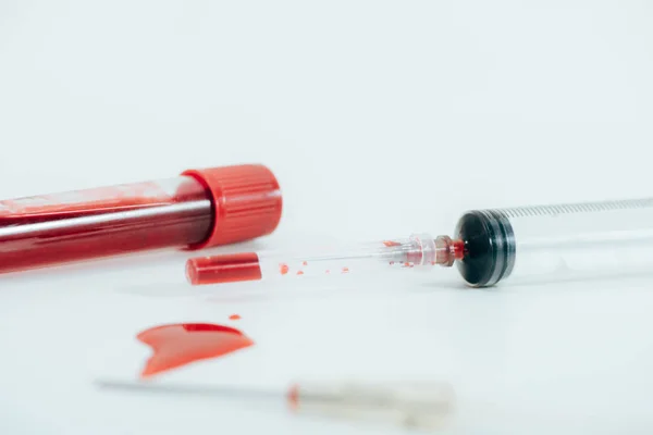 Test tube with blood and syringe on white surface — Stock Photo