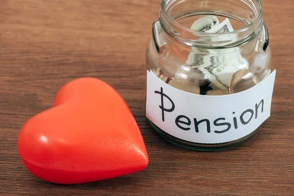 Plastic heart and piggy bank on wooden surface — Stock Photo