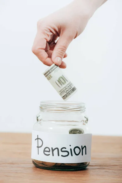 Partial view of man putting dollar banknote in piggy bank isolated on white — Stock Photo