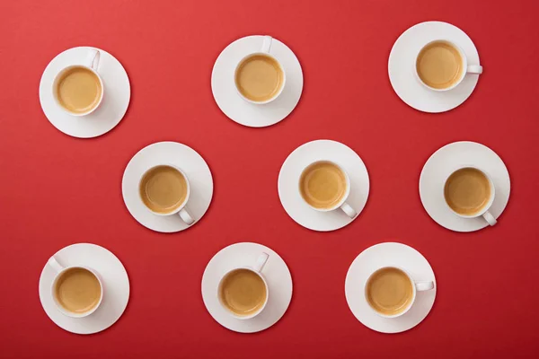 Vista superior de tazas blancas con café sobre fondo rojo - foto de stock