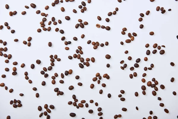 Вид зверху на кавові зерна, розкидані на білому тлі — стокове фото