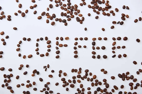 Vista dall'alto di lettering caffè fatto di chicchi di caffè marrone su sfondo bianco — Foto stock