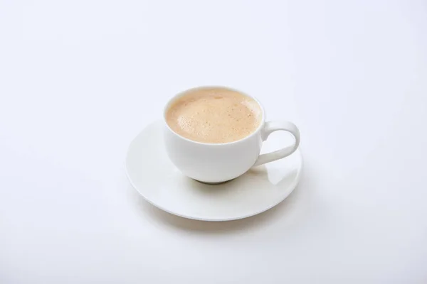 Delicious coffee with foam in cup on saucer on white background — Stock Photo