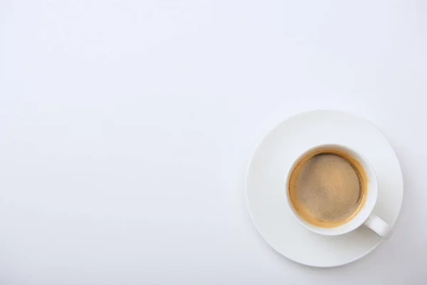 Vue du dessus de délicieux café avec mousse dans une tasse sur soucoupe sur fond blanc avec espace de copie — Photo de stock