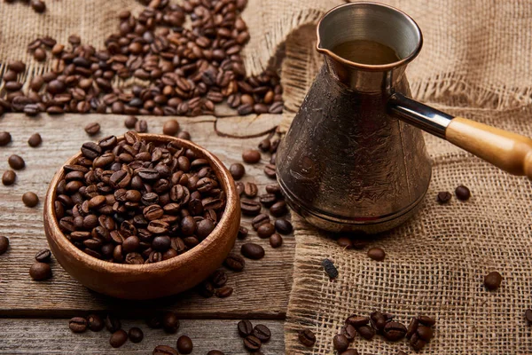 Cezve vicino chicchi di caffè in ciotola su sfondo di legno — Foto stock