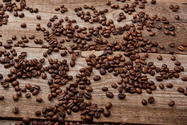 Mesa rústica de madera con granos de café tostados dispersos - foto de stock