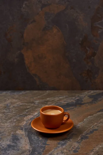 Delicioso café en taza marrón en platillo sobre mesa de mármol - foto de stock