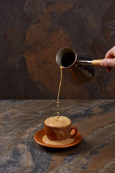 Обрізаний вид на людину, що виливає каву з кави в чашку на мармуровій поверхні — стокове фото