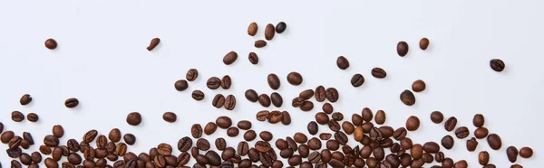 Tiro panorâmico de grãos torrados marrons espalhados no fundo branco — Fotografia de Stock