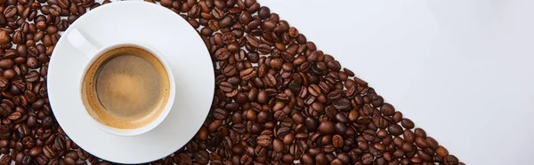 Tiro panorâmico de café saboroso na xícara no pires perto de grãos torrados — Fotografia de Stock