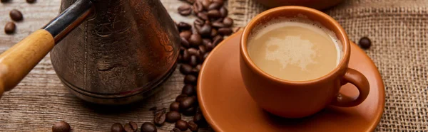 Панорамний знімок кавових зерен в мисці і джеве біля чашки кави на дерев'яному фоні — стокове фото