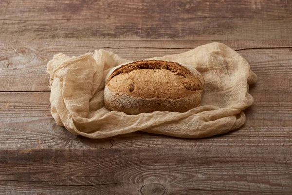 Pão assado fresco no pano na mesa de madeira — Fotografia de Stock