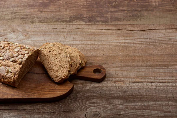 Pain frais coupé sur planche à découper sur table en bois — Photo de stock