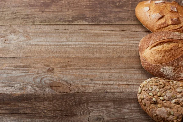 Pains frais cuits au four sur table rustique en bois — Photo de stock