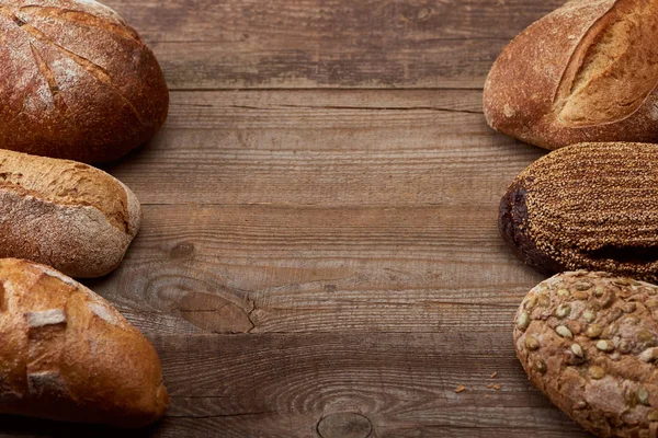 Panes recién horneados de sabroso pan sobre mesa rústica de madera con espacio para copiar - foto de stock