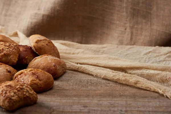 Deliciosos panes sobre mesa rústica de madera con saco sobre fondo - foto de stock