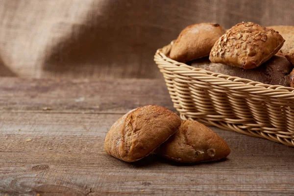 Deliziosi panini freschi in scatola di vimini su tavolo rustico in legno con spazio copia — Foto stock