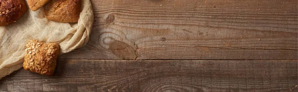 Vista superior de pães assados frescos em pano na mesa de madeira, tiro panorâmico — Fotografia de Stock