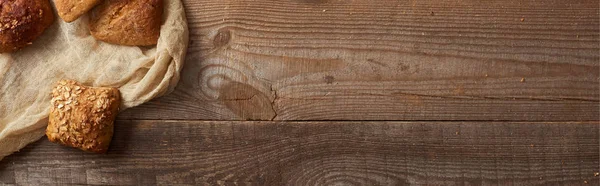 Top view of fresh baked buns on cloth on wooden table, panoramic shot — Stock Photo