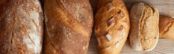 Vista superior de pães caseiros frescos de pão e pão na mesa rústica de madeira, tiro panorâmico — Fotografia de Stock