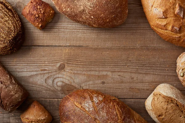 Blick von oben auf hausgemachte Brotlaibe und Semmeln auf einem rustikalen Holztisch mit Kopierraum — Stockfoto