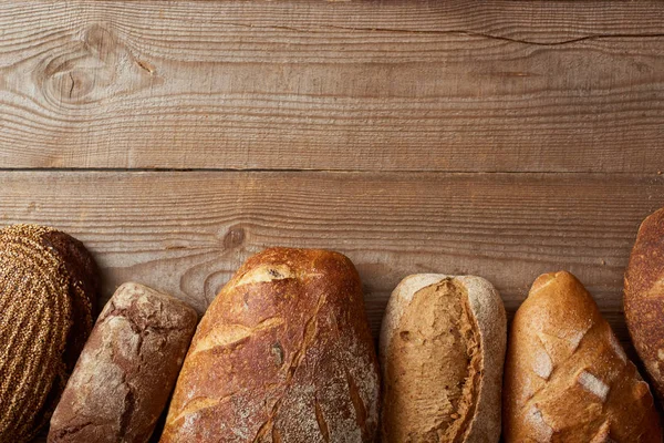 Top view of fresh homemade loaves of bread on wooden table with copy space — Stock Photo