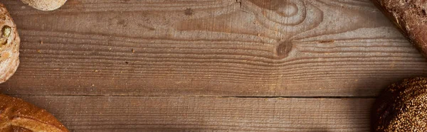 Vista dall'alto del pane fresco fatto in casa su tavolo marrone in legno con spazio copia, colpo panoramico — Foto stock