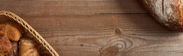 Weidenkorb mit Brötchen und Brotlaib auf Holztisch, Panoramaaufnahme — Stockfoto