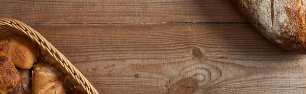 Vista dall'alto del cesto di vimini con focacce e pagnotta sul tavolo di legno, colpo panoramico — Foto stock