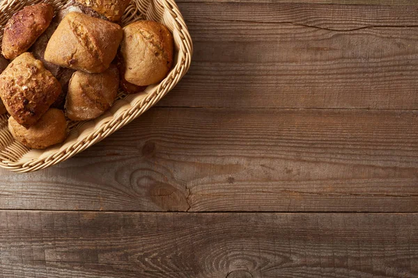 Weidenkorb mit Brötchen auf Holztisch von oben — Stockfoto