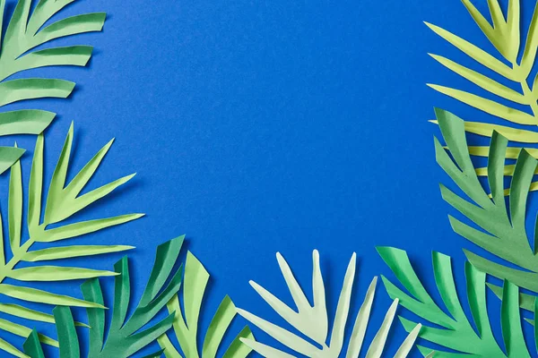 Vue du dessus des feuilles tropicales coupées en papier vert sur fond bleu avec espace de copie — Photo de stock