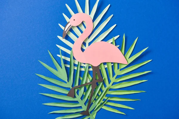 Top view of green paper cut exotic leaves and flamingo on blue background — Stock Photo