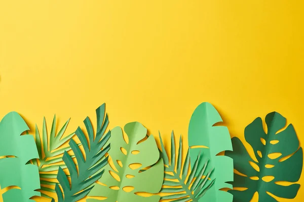 Vista dall'alto di foglie di palma verde taglio carta su sfondo giallo con spazio copia — Foto stock
