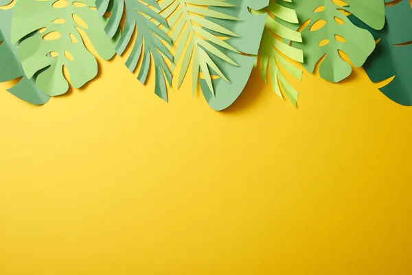Top view of paper cut green palm leaves on yellow background with copy space — Stock Photo