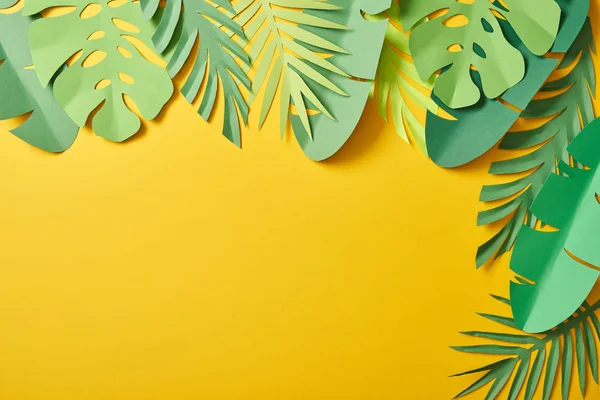 Top view of paper cut green palm leaves on yellow background with copy space — Stock Photo