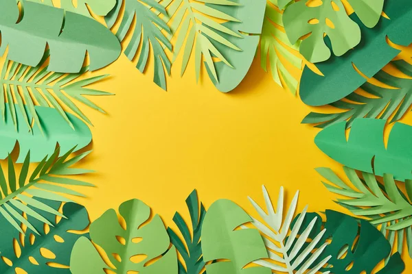 Top view of paper cut green palm leaves on yellow background with copy space — Stock Photo