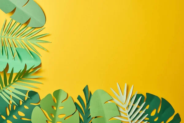 Top view of paper cut green palm leaves on yellow background with copy space — Stock Photo