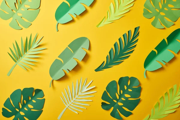 Top view of paper cut green palm leaves on yellow background, seamless pattern — Stock Photo